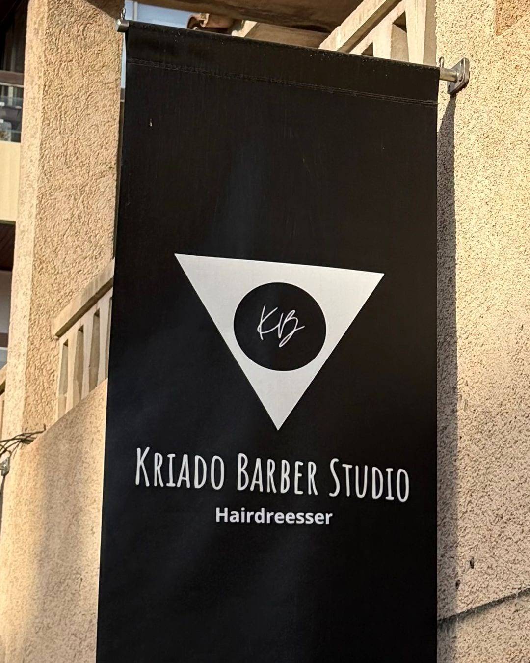La banderola de Kriado Barber Studio en la fachada